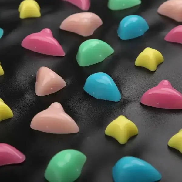 Zoom sur les picots multicolores du tapis de réflexologie pour massage des pieds, galets en plastique rose bleu vert jaune sur fond noir
